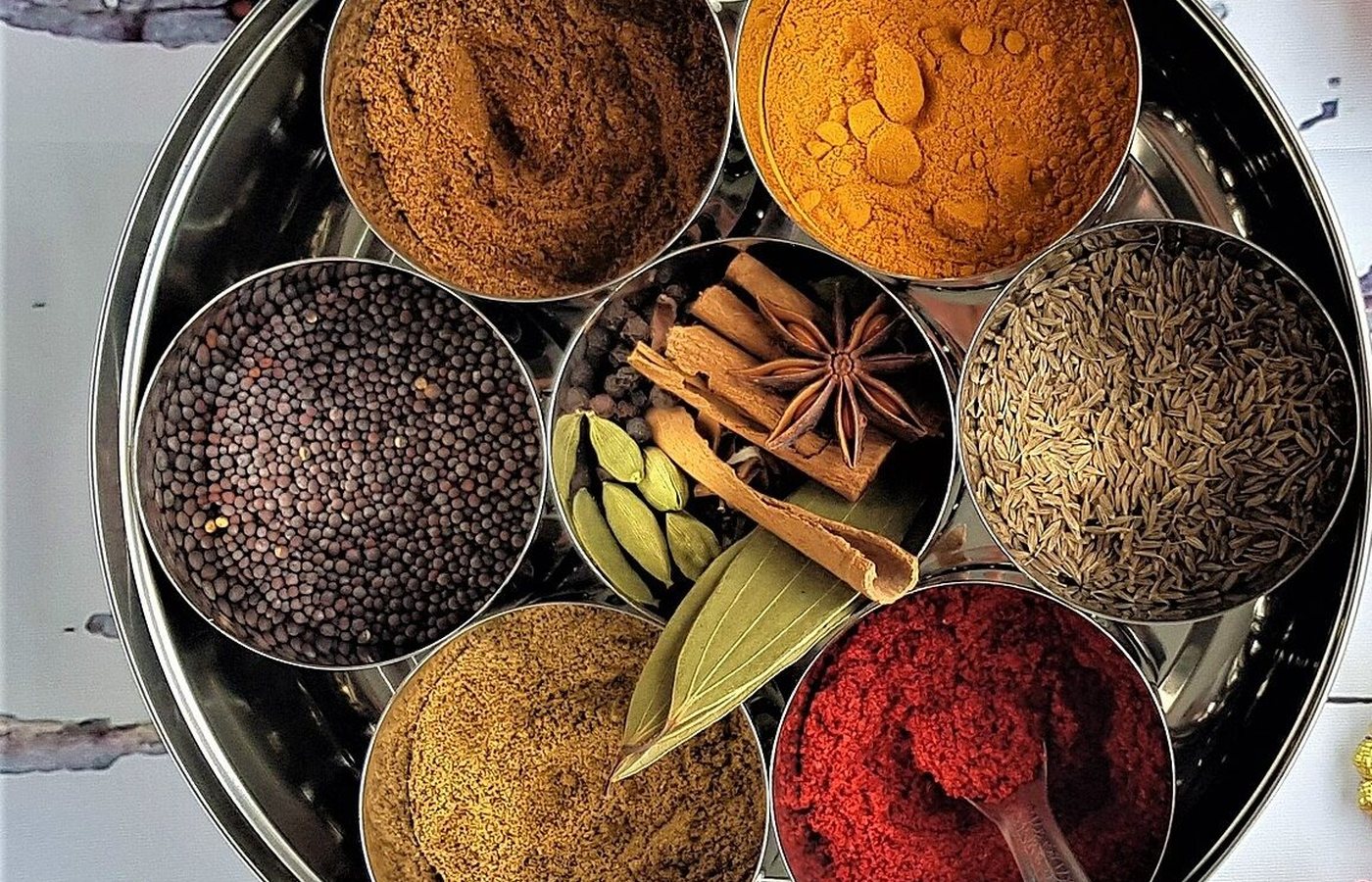 A steel masala dabba with turmeric, chilli, cumin, mustard seed, cardamom and cinnamon